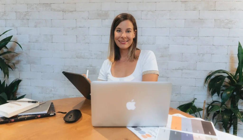 Klaudia Pawelec – absolwentka Kursu Projektowania Graficznego w Akademii Projektowania Weroniki Wolskiej – przy biurku z laptopem i tabletem graficznym, podczas pracy nad projektami z zakresu grafiki komputerowej, identyfikacji wizualnej i designu. Obraz ukazuje środowisko pracy freelancera-grafika i proces twórczy w branży kreatywnej, oparty na wiedzy zdobytej dzięki nauce projektowania graficznego online.