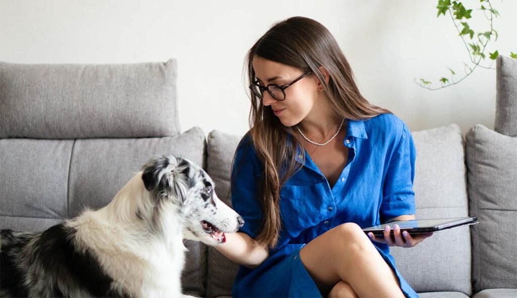 Portret Karoliny Krajewskiej – projektantki graficznej, freelancerki i absolwentki Kursu Projektowania Graficznego w Akademii Projektowania, przedstawiony w artykule Weroniki Wolskiej. Zdjęcie pokazuje Karolinę w jej naturalnym, zawodowym środowisku – z tabletem graficznym, w minimalistycznym wnętrzu, w otoczeniu sztuki i designu. Fotografia wspiera autentyczność i wiarygodność treści, jednocześnie odwołując się do tematów: freelancing, grafika komputerowa, kreatywna praca, kobieta w branży kreatywnej, projektowanie graficzne, edukacja artystyczna.