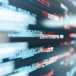 Dynamiczne dane cyfrowe i rozmazane linie kodu symbolizujące działanie algorytmów sztucznej inteligencji generującej grafikę komputerową, podkreślają wpływ AI na przyszłość pracy grafika. Grafika odnosi się do tematyki podejmowanej przez Weronikę Wolską w ramach Kursu Projektowania Graficznego w Akademii Projektowania, gdzie omawiane są wyzwania, jakie niesie zastosowanie sztucznej inteligencji, automatyzacja, generatory obrazów AI Art i narzędzia takie jak Canva w pracy grafika komputerowego. Obraz ukazuje transformację narzędzi pracy grafika i ewolucję zawodu artysty grafika w erze cyfrowej.