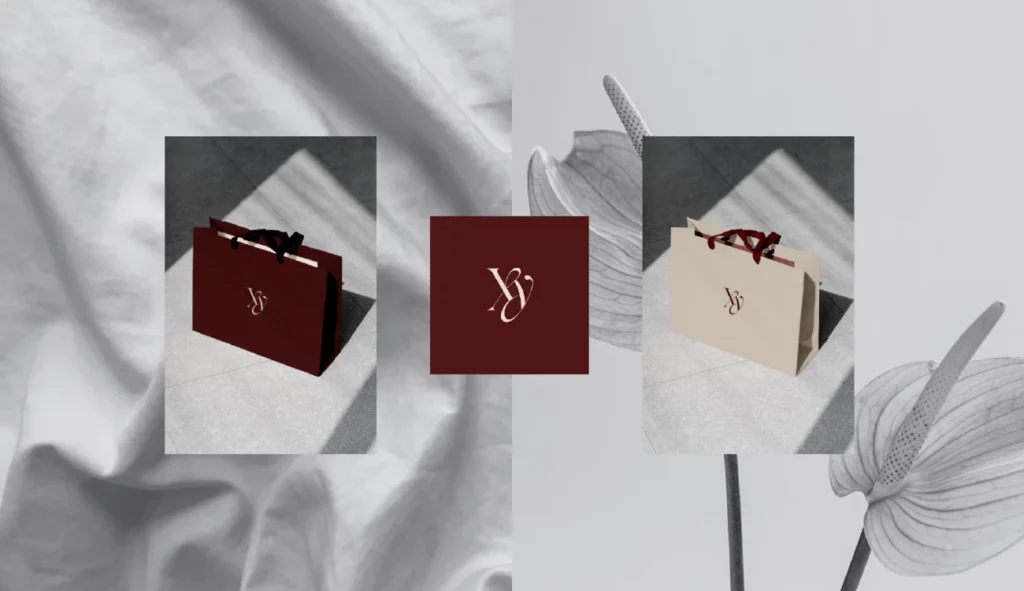 Początki w branży graficznej. Projekt brandingowy Sary Zimorodzkiej – absolwentki Kursu Projektowania Graficznego w Akademii Projektowania Weroniki Wolskiej – prezentujący wizualizacje eleganckich toreb papierowych w dwóch wersjach kolorystycznych: głębokiego bordo i subtelnego beżu. Obie torby ozdobione są minimalistycznym monogramem „YJ” oraz wykończone satynowymi, czerwonymi i czarnymi wstążkami. W centrum projektu znajduje się kwadratowy element z tym samym monogramem w złamanej bieli na tle bordo. Ujęcia wykonane są w estetyce premium, z subtelnym światłocieniem, podkreślając profesjonalizm w obszarze designu, grafiki komputerowej i projektowania opakowań dla marek luksusowych.