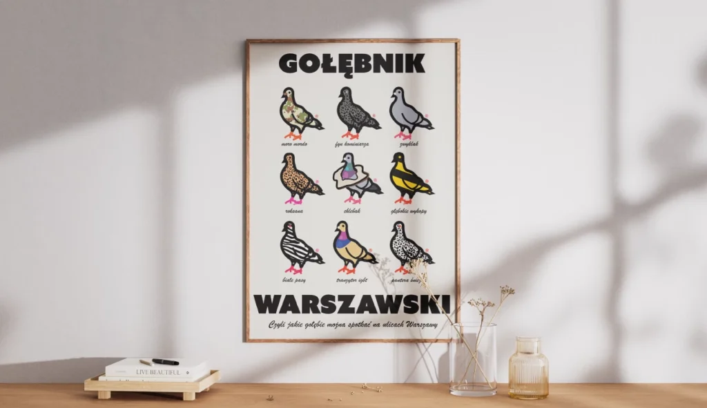 Plakat w drewnianej ramie zatytułowany „Gołębnik Warszawski” autorstwa Sary Zimorodzkiej, absolwentki Kursu Projektowania Graficznego w Akademii Projektowania Weroniki Wolskiej. Ilustracja przedstawia dziewięć kolorowych, stylizowanych graficznie gołębi z zabawnymi podpisami, takimi jak „mora morda” czy „trawnikowy styl”, prezentując kreatywne wykorzystanie designu, ilustracji i grafiki komputerowej w praktyce. Plakat stanowi przykład pracy freelancera w obszarze projektowania graficznego, łączący poczucie humoru z profesjonalnym opracowaniem wizualnym.