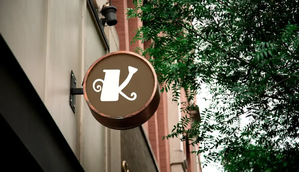 Szyld z literą „K” zaprojektowany w stylu retro, umieszczony na elewacji budynku – przykład identyfikacji wizualnej wykonanej przez Dorotę Kozioł, absolwentkę Kursu Projektowania Graficznego w Akademii Projektowania Weroniki Wolskiej. To praca pokazująca praktyczne wykorzystanie umiejętności z zakresu grafiki komputerowej, designu i projektowania graficznego, które pozwalają freelancerom i grafikom działać na swoim w branży kreatywnej.